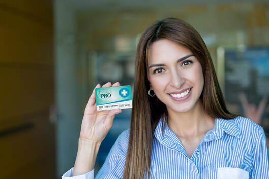 Portrait of beautiful female patient holding a medical business card looking at camera smiling 